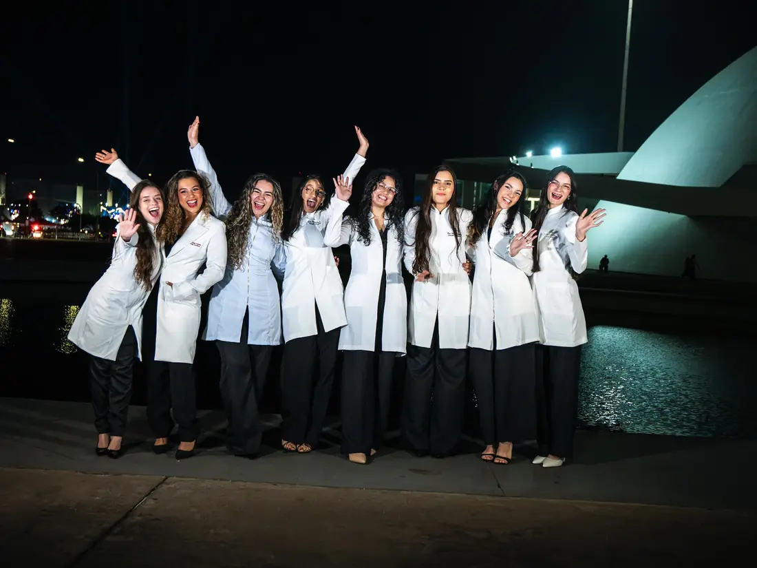 Turma de formandas de jaleco comemorando à noite