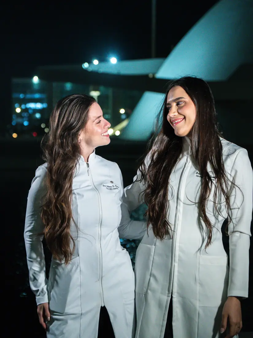 Duas formandas de jaleco rindo juntas