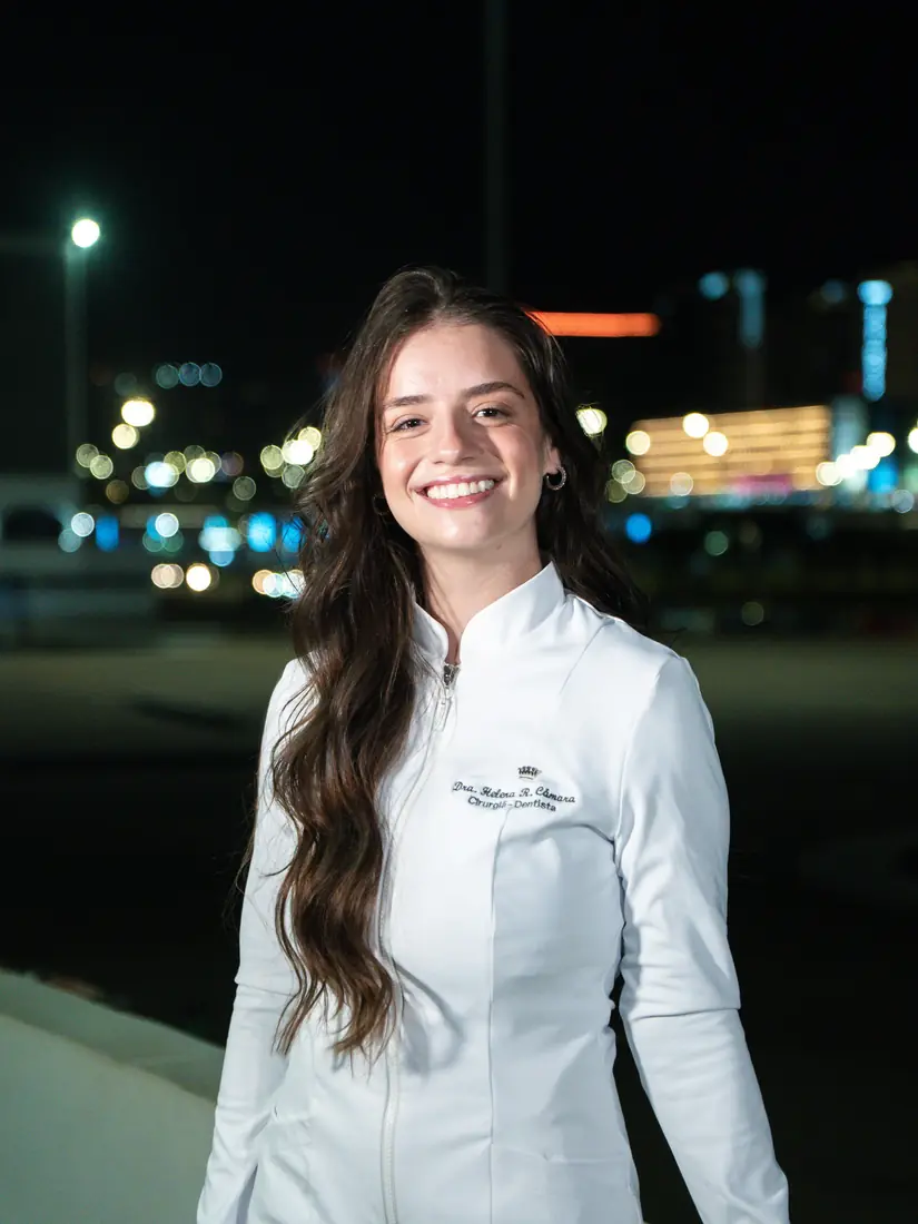 Formanda de jaleco à noite com a cidade ao fundo